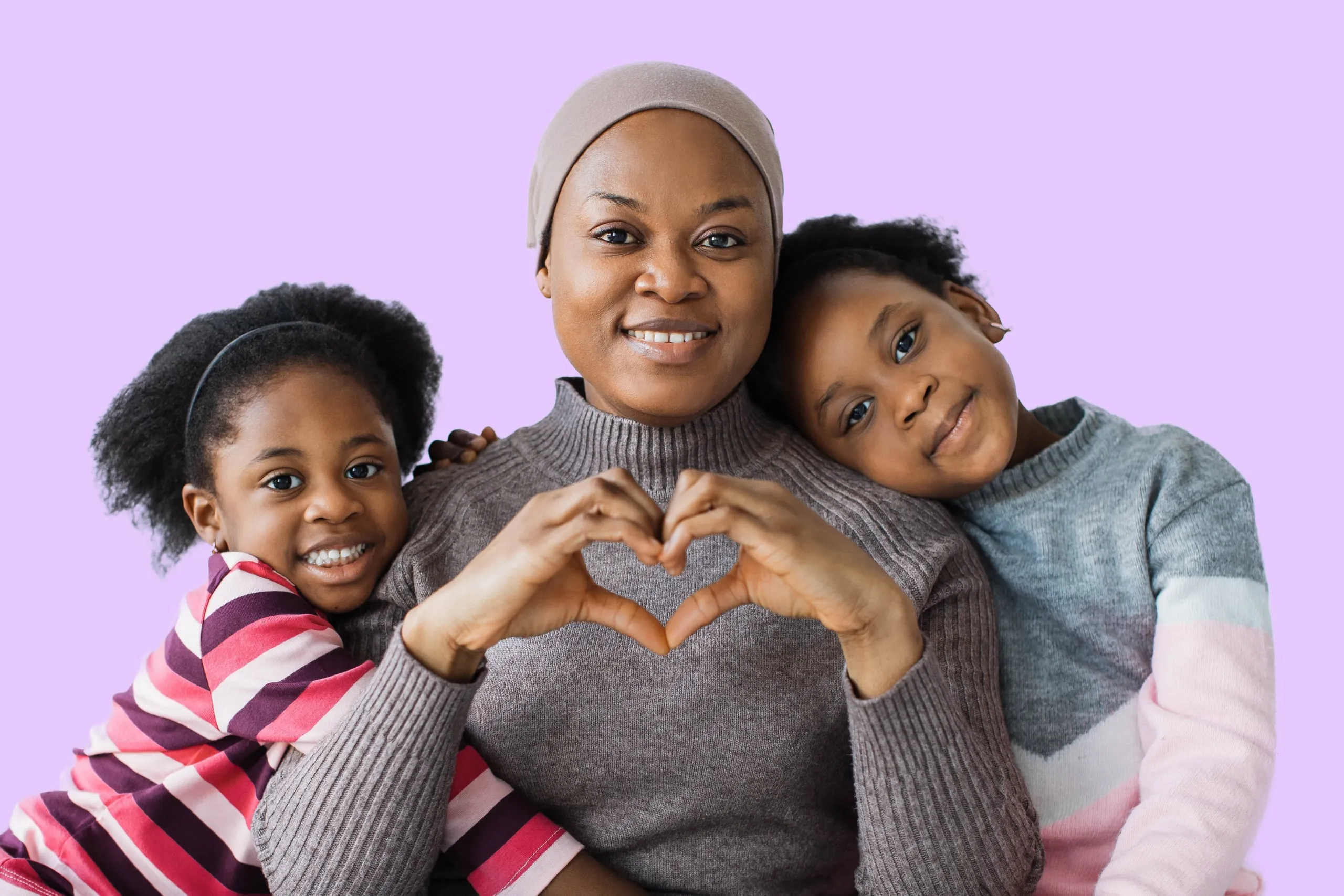 A smiling mother with her two children, making a heart with their hands