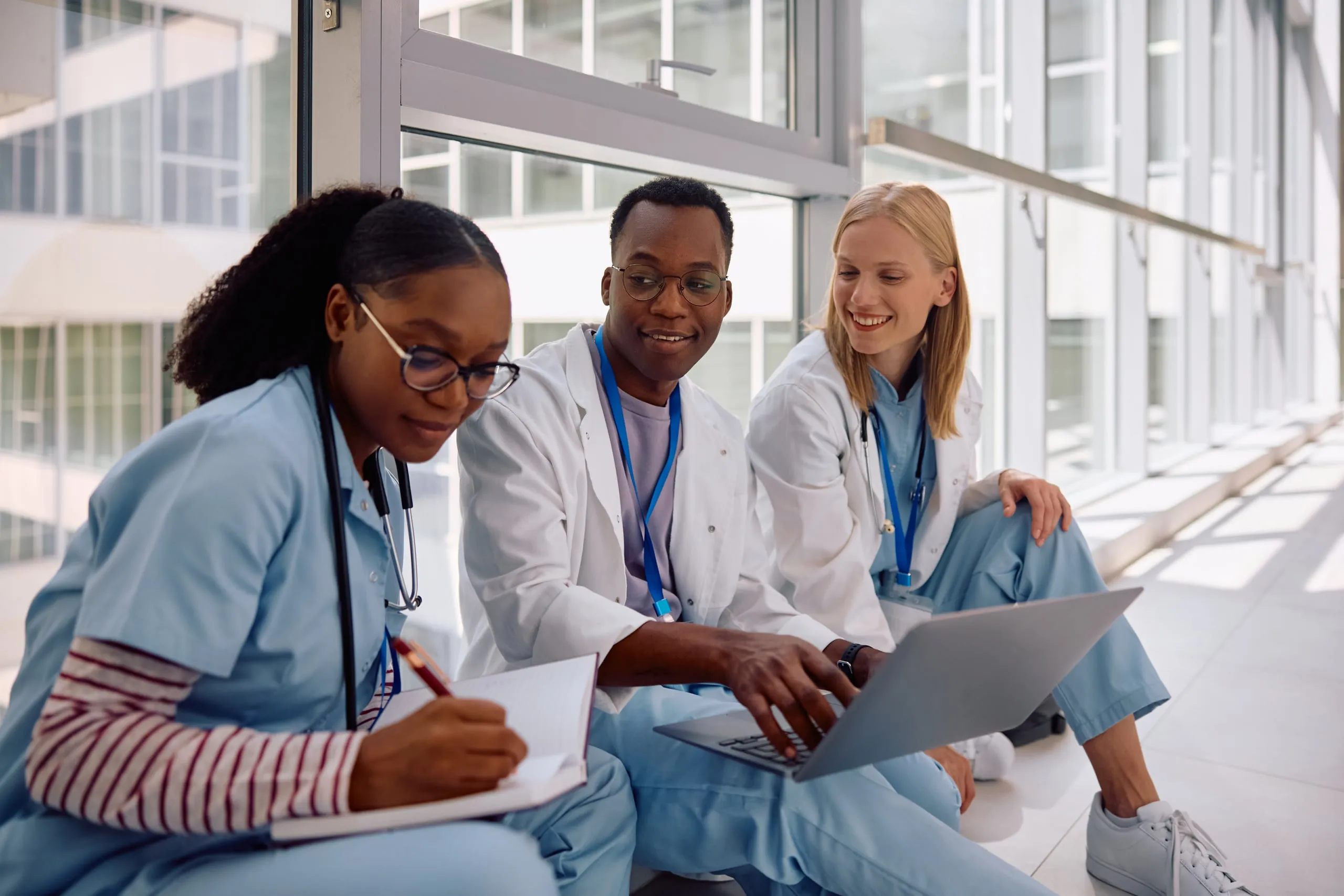 Three health workers sitting together, reviewing notes and a laptop