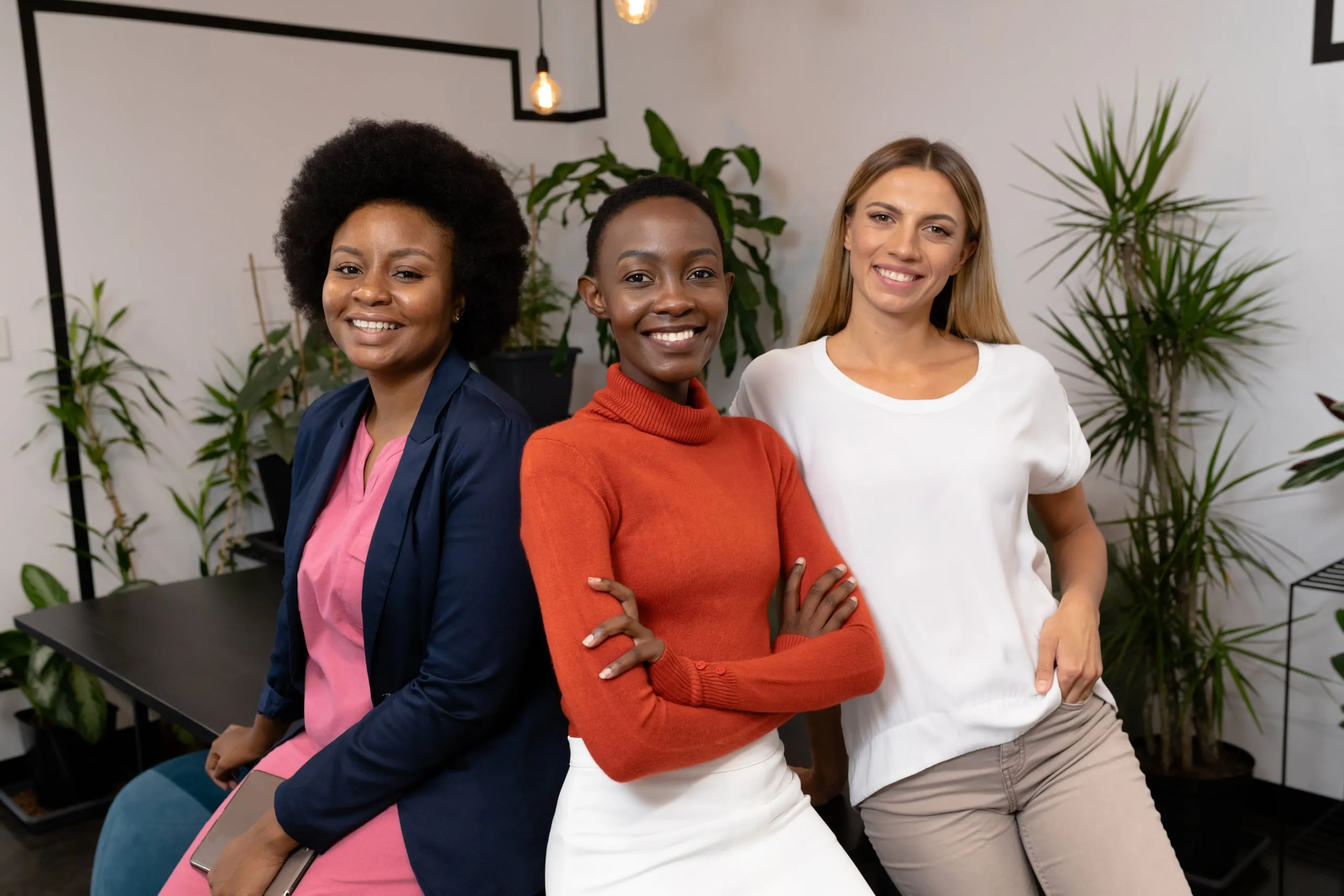 Three smiling women standing together in an office
