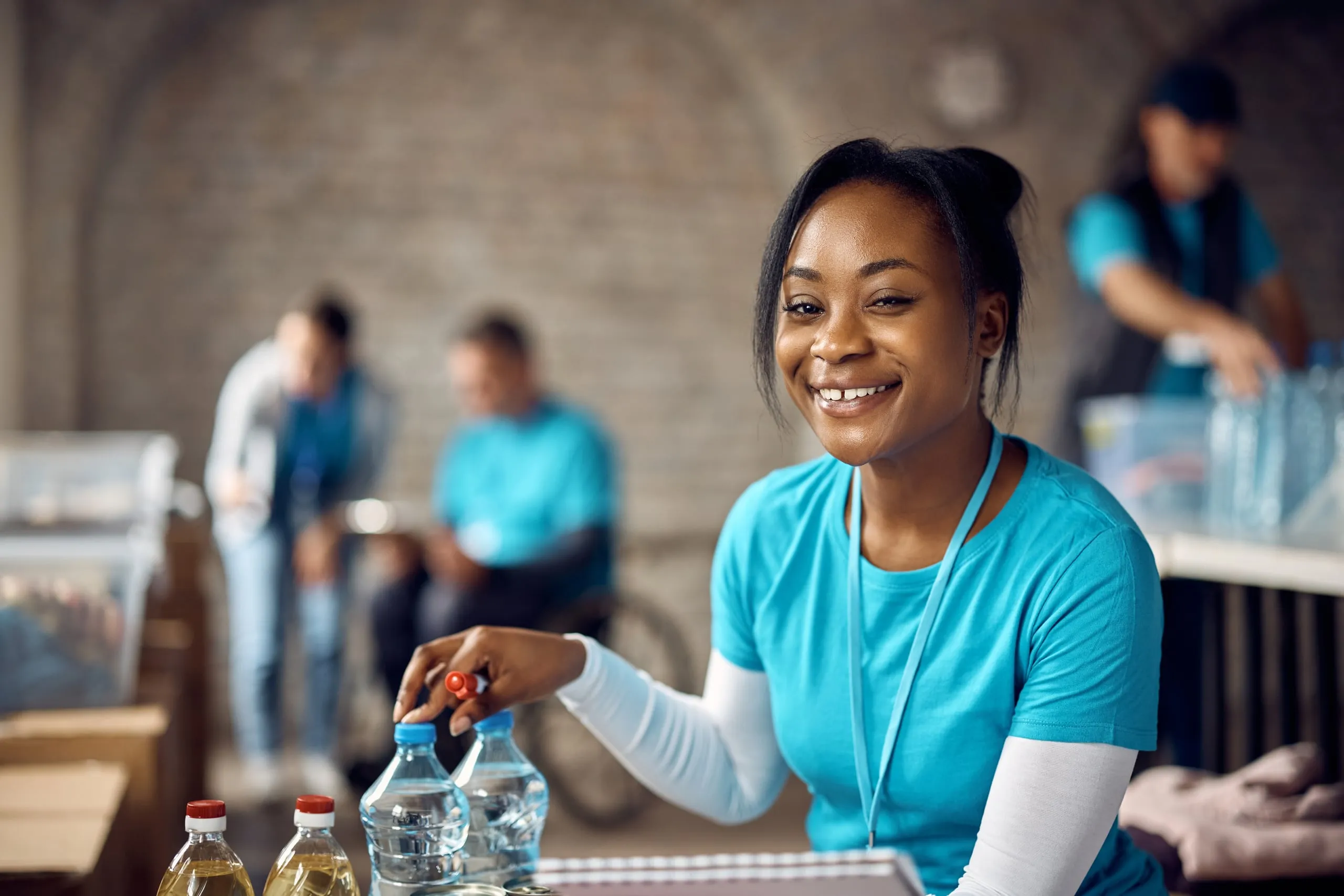 A smiling volunteer sorting bottled water at a table